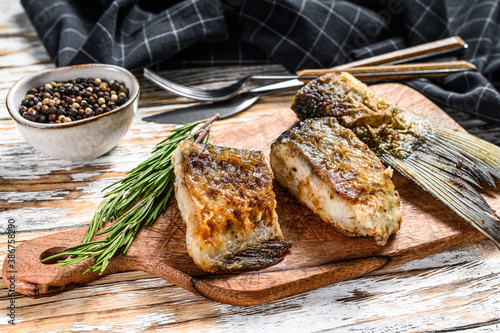 Grilled river fish silver carp on a cutting board. Wooden background. Top view.