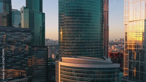 Moscow city glass skyscrapers drone pan shot left to right, close to the buildings windows, sun reflection in the windows. Moscow International Business Center at the sunset, evening