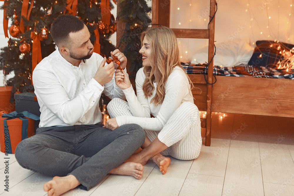 Couple near christmas tree. Lady in a white pajamas. Man in a white shirt. Couple near christmas tree. Lady in a white pajamas. Man in a white shirt.