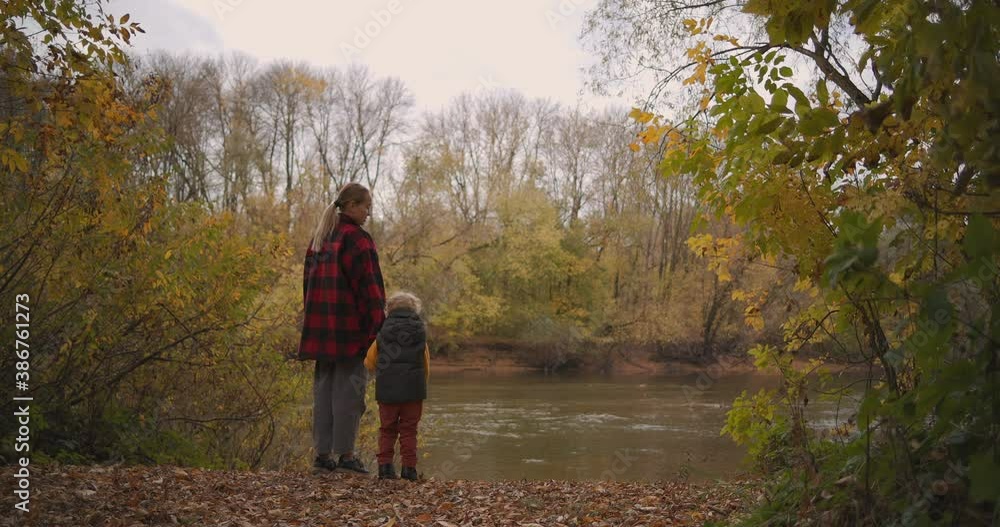 calm weekend trip at nature, little boy with her mother are standing in forest and looking on lake, enjoying landscape at autumn day calm weekend trip at nature, little boy with her mother are standing in forest and looking on lake, enjoying landscape at autumn day