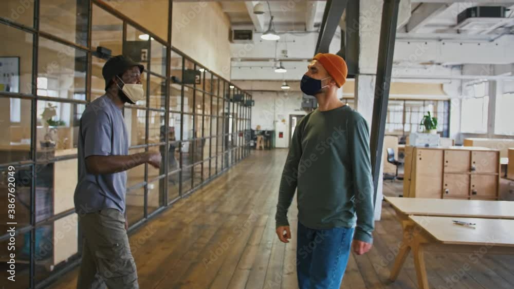 Health care and new normal for colleagues. Diverse coworkers in protective masks greeting by elbows in office Health care and new normal for colleagues. Diverse coworkers in protective masks greeting by elbows in office