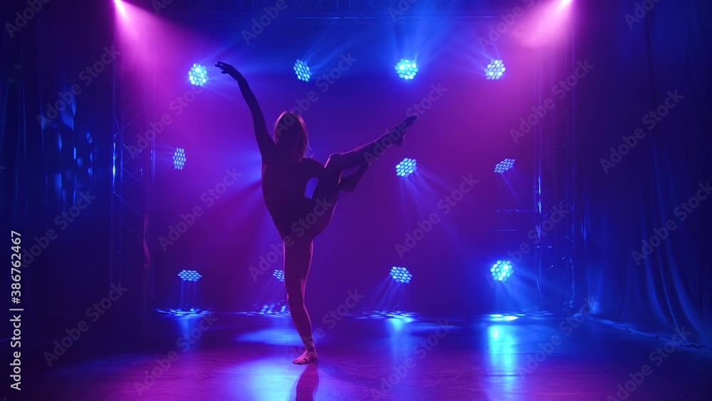 Sexy modern contemporary dance contempt performed by a flexible young woman. The dancer is enjoying the dance and hovering in a dark studio with neon lights. Silhouette. Slow motion. Sexy modern contemporary dance contempt performed by a flexible young woman. The dancer is enjoying the dance and hovering in a dark studio with neon lights. Silhouette. Slow motion.