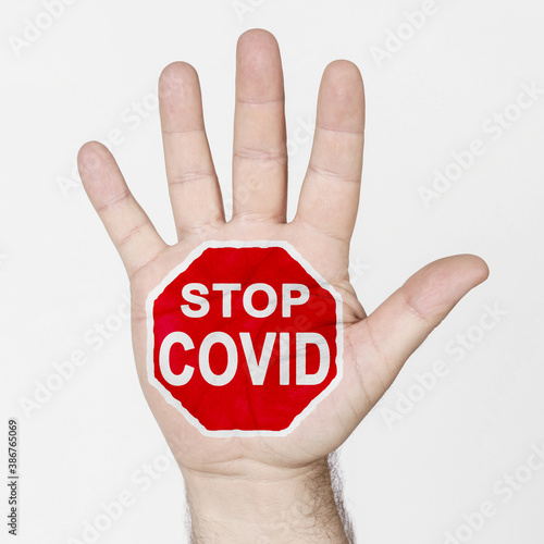 On the palm of the hand there is a stop sign with the inscription - STOP COVID. Isolated on white background.