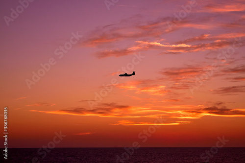 View of an airplane flying at sunset light.