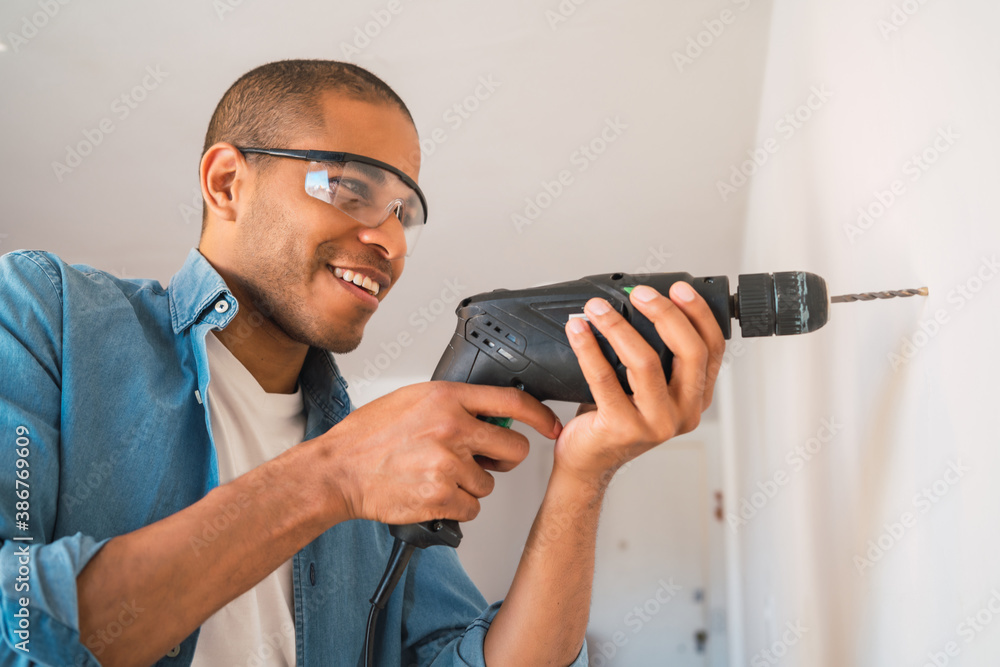 Young man with a electric drill and making hole in wall. Young man with a electric drill and making hole in wall.