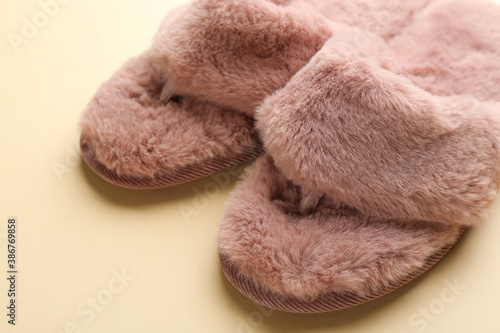 Pair of stylish soft slippers on beige background, closeup