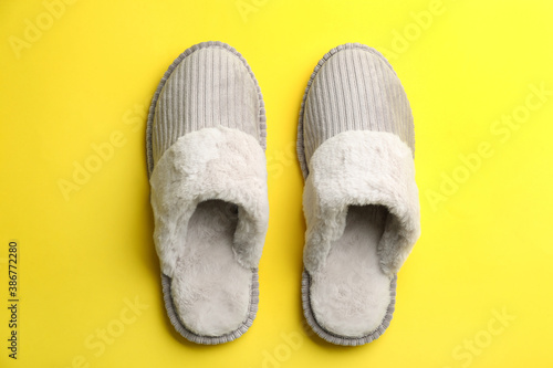 Pair of soft slippers on yellow background, flat lay