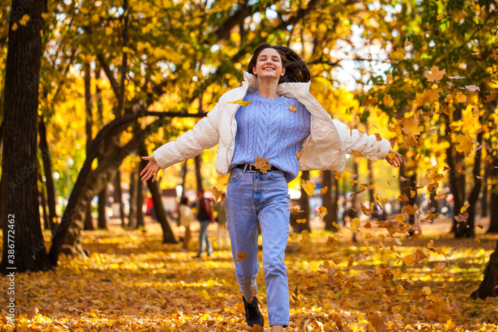 Happy young girl running in the autumn park