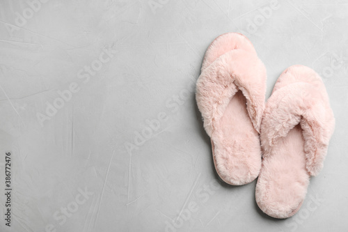 Pair of soft slippers on light grey background, flat lay. Space for text
