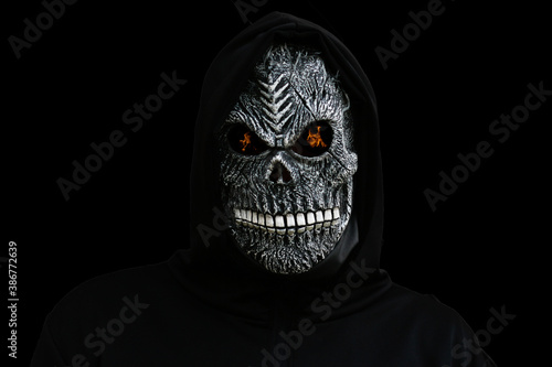 Isolated man dressed in death carnival costume on black background with fire on eyes. Halloween holiday concept. Scary death portrait. Death mask on white background. Dark horror. Selective focus.