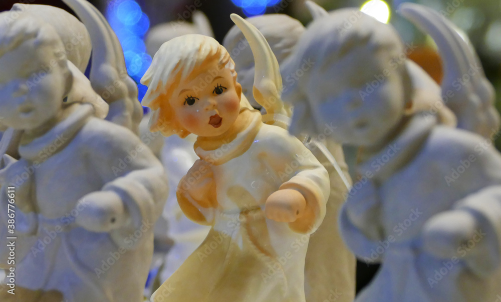 Fototapeta premium Painted ceramic figure with wings stands between unpainted figures