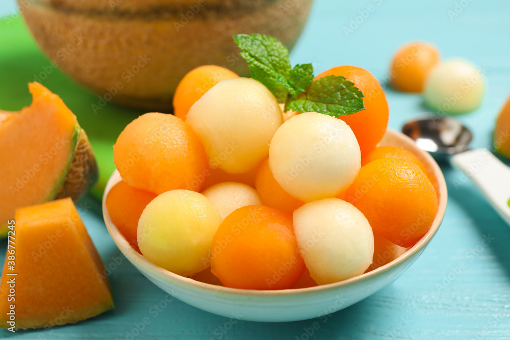 Melon balls and mint in bowl on light blue table, closeup