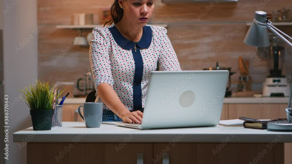 Woman yawning while working remotly from home late at night in the kitchen. Busy exhausted employee using modern technology network wireless doing overtime for job reading typing, searching Woman yawning while working remotly from home late at night in the kitchen. Busy exhausted employee using modern technology network wireless doing overtime for job reading typing, searching