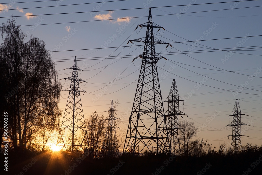 Electric powerlines. High voltage power lines, pylons over sunrise with sun