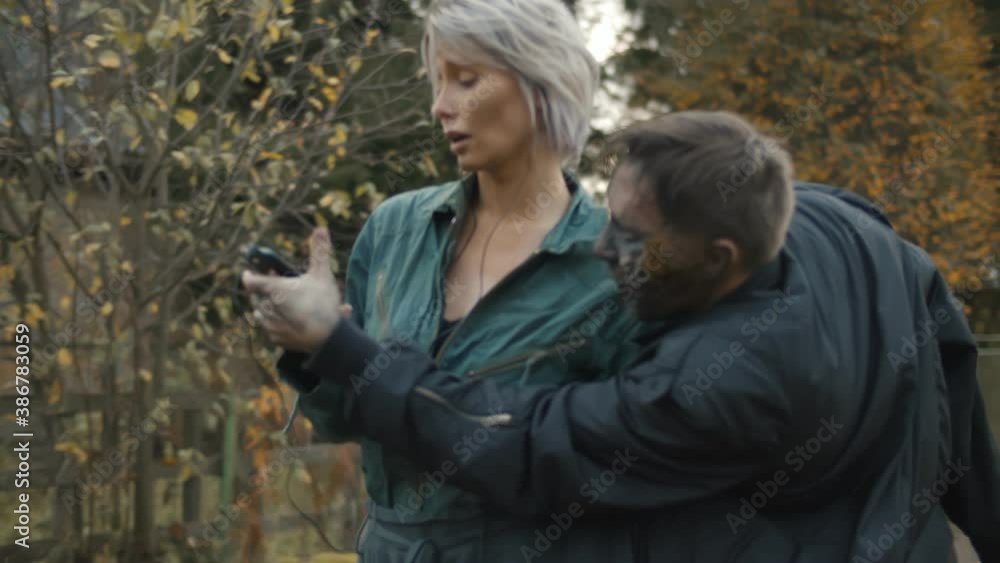 Clumsy zombie thief trying to take smartphone away from y woman walking outdoors Clumsy zombie thief trying to take smartphone away from y woman walking outdoors