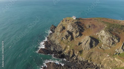 Remote house on green clifftop beside blue ocean, South Devon coast, England photo