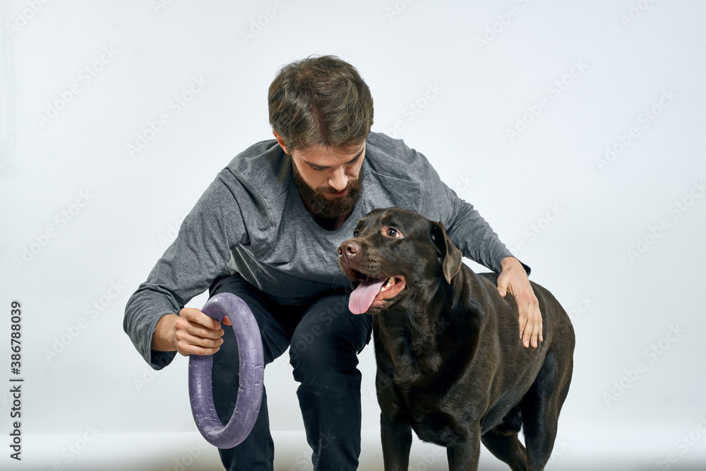 Man with dog training gray ring doing exercises pets light background. Man with dog training gray ring doing exercises pets light background.