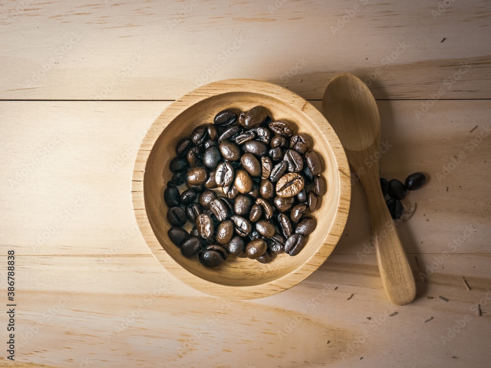 coffee beans in wood bowl top view on wooden table for food content. coffee beans in wood bowl top view on wooden table for food content.