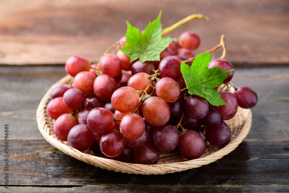 Fresh red grapes fruit in a basket on wooden background Fresh red grapes fruit in a basket on wooden background