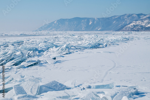 Snow-covered landscape of the clean lake Baikal. Fragments, blocks of transparent ice. Winter landscape for background, banners.