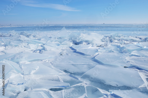 Crystal clear ice of Lake Baikal. Shards of ice  cracks on the surface. Winter landscape for background  banners.