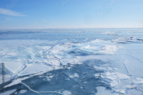 Crystal clear ice of Lake Baikal. Shards of ice, cracks on the surface. Winter landscape for background, banners.