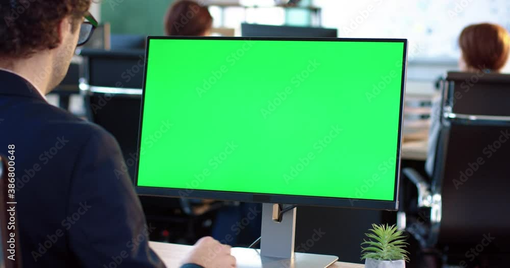 Close up of monitor in office. Green screen. Employee working at computer sitting at desk. View from back. Close up of monitor in office. Green screen. Employee working at computer sitting at desk. View from back.