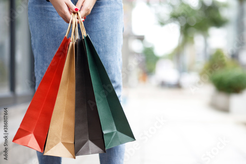 Closeup of woman hand holding shopping bag colorful paper on the street happy summer with copy space.