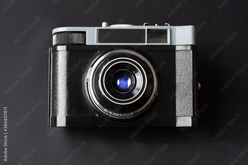 Retro film photo camera with blue lens reflection on black background. Top view. Close up Retro film photo camera with blue lens reflection on black background. Top view. Close up