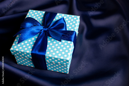 Blue gift box with a bow on a blue background. Holiday greeting card.