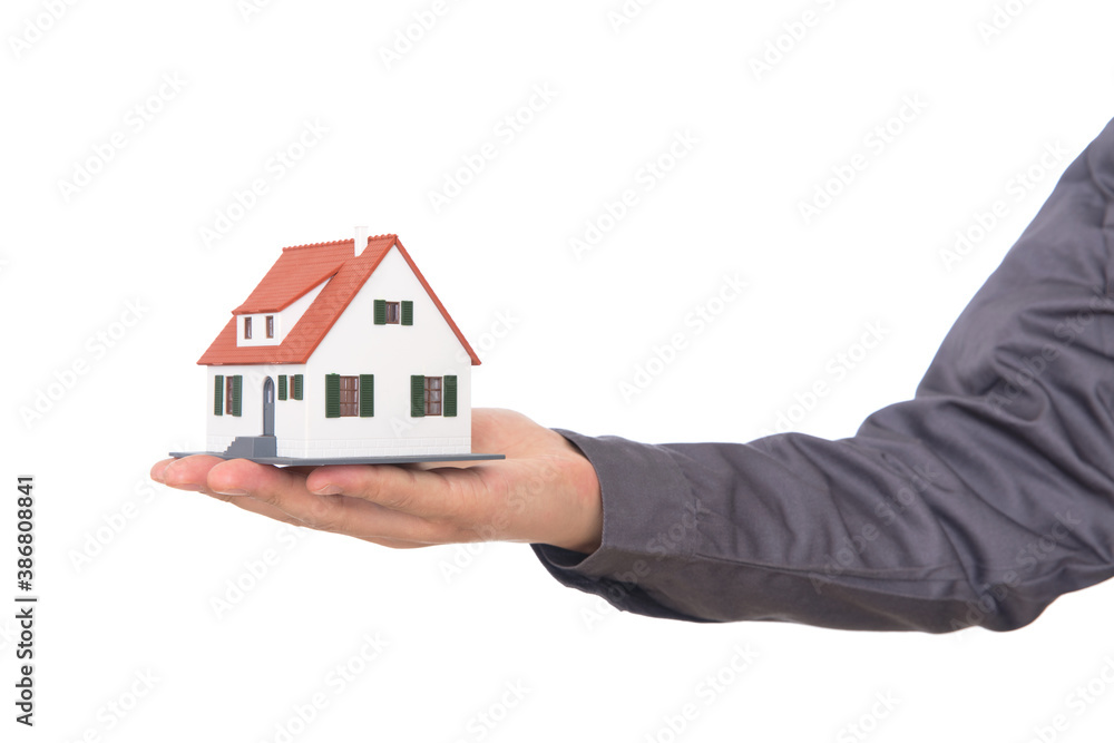 Closeup of hand holding house model in front of white background Closeup of hand holding house model in front of white background