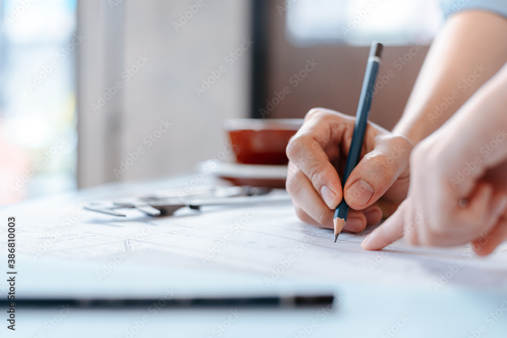 engineers holding a pen pointing to a building and drawing outlay construction plan as guide for builders with details. Engineer design and writing blueprint. engineers holding a pen pointing to a building and drawing outlay construction plan as guide for builders with details. Engineer design and writing blueprint.