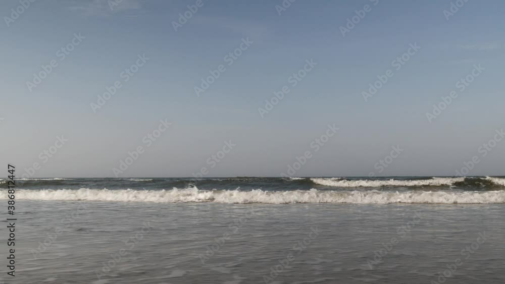 Low angle view on sea waves rolling on sandy beach