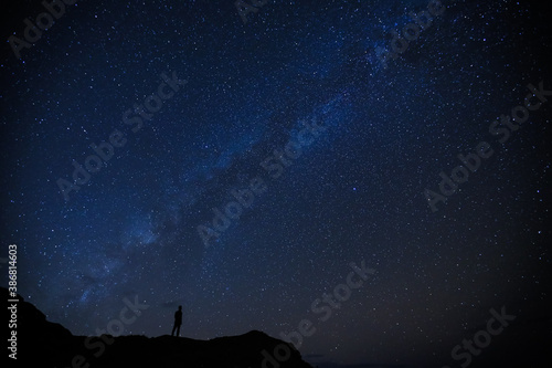 Silhouette of boy / man standing on the hill. Stargazing at Oahu island, Hawaii. Starry night sky, Milky Way galaxy astrophotography.