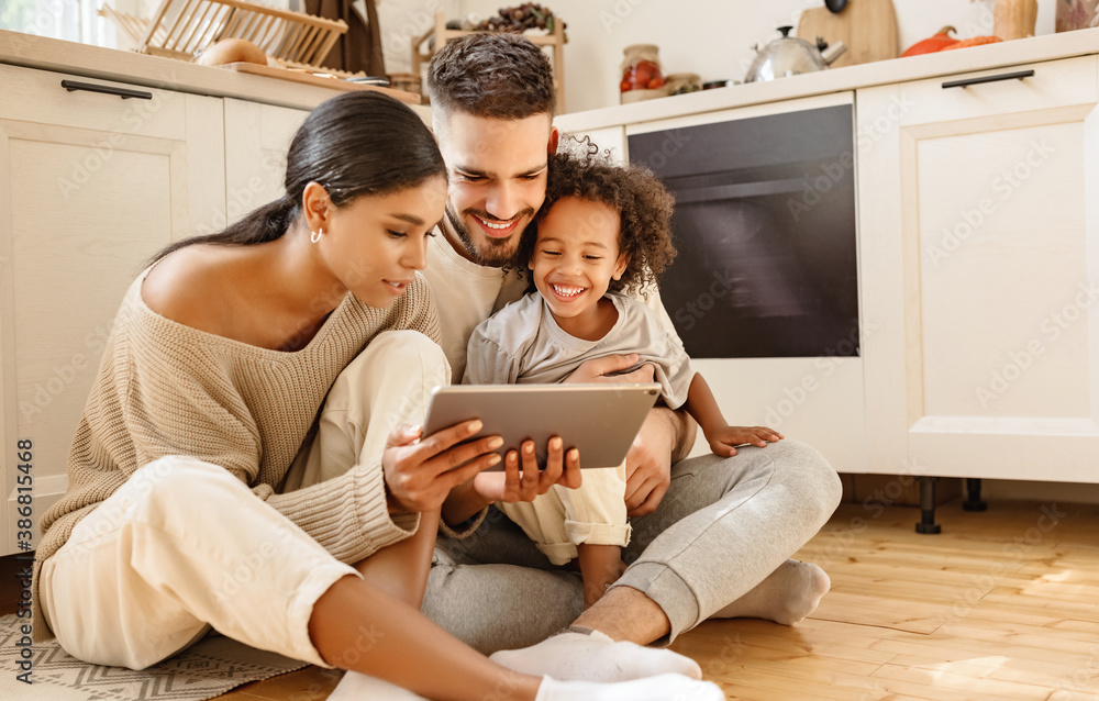 happy multi ethnic family: parents and son using tablet  at home - obrazy, fototapety, plakaty 