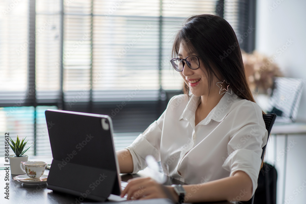 Pretty, charming asian business woman working with digital tablet at modern desk. Pretty, charming asian business woman working with digital tablet at modern desk.