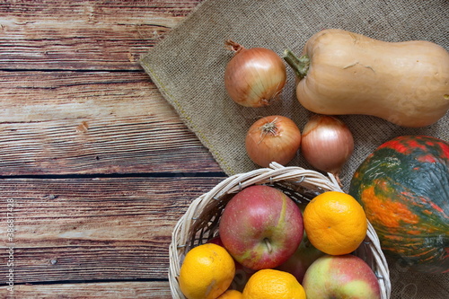 Autumn composition with pumpkin, onion, apple and tangerine on wooden background