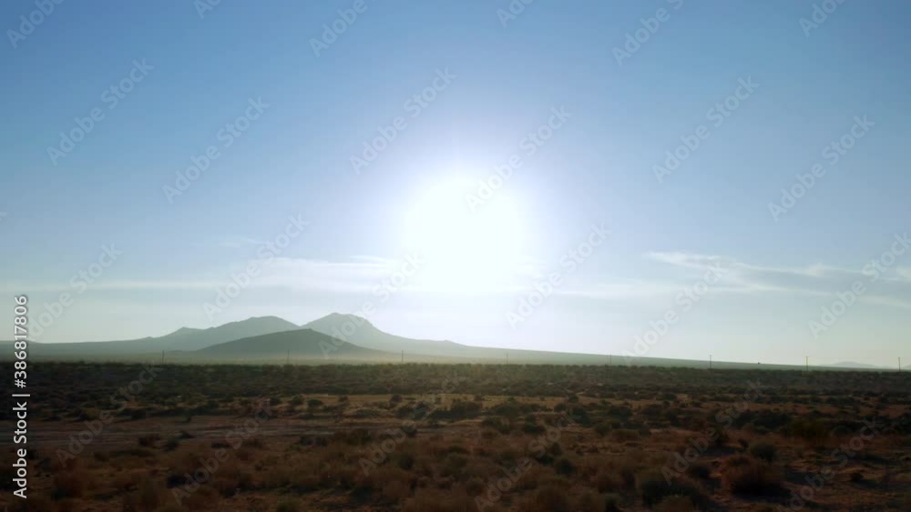 Flying over the Mojave Desert while looking toward the distant mountains and hot sun on a summer morning Flying over the Mojave Desert while looking toward the distant mountains and hot sun on a summer morning