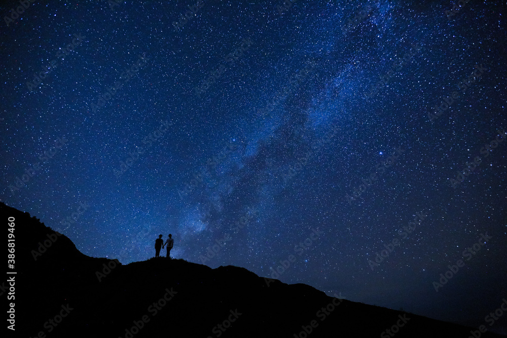 Silhouette of two girls / women on the hill.  Stargazing at Oahu island, Hawaii. Starry night sky, Milky Way galaxy astrophotography.