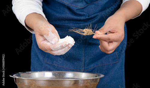 The chef is holding a pinch of flour and a wheat ear