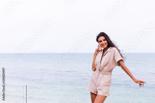Romantic portrait of woman in long dress on beach at windy cloudy day. 