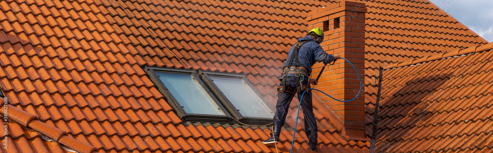  high-altitude worker washing the roof with pressurized water - obrazy, fototapety, plakaty 