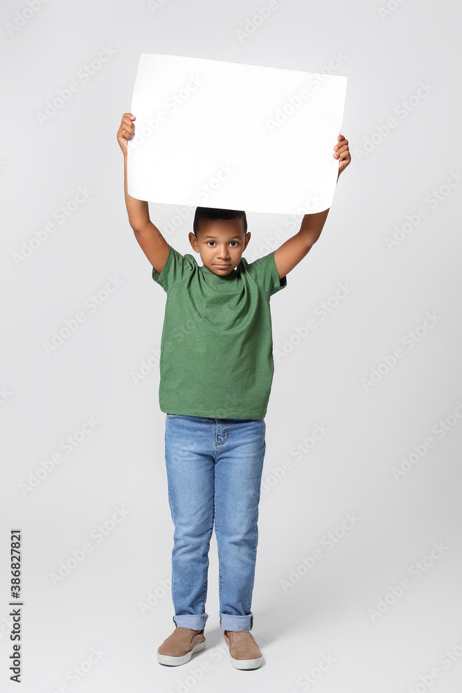 Little African-American boy with blank poster on light background Little African-American boy with blank poster on light background