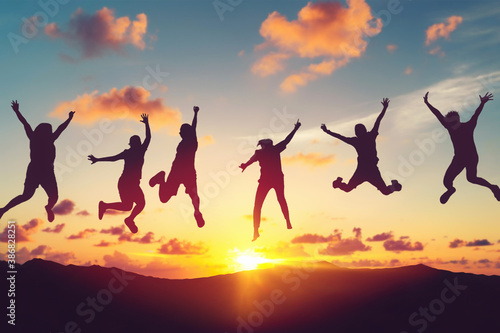 Silhouette happy friends jump at top of mountain on sunset sky abstract background. Copy space of feel good freedom and travel adventure concept.