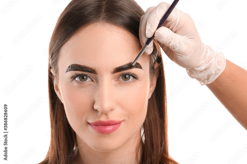 Young woman undergoing eyebrow correction procedure on white background