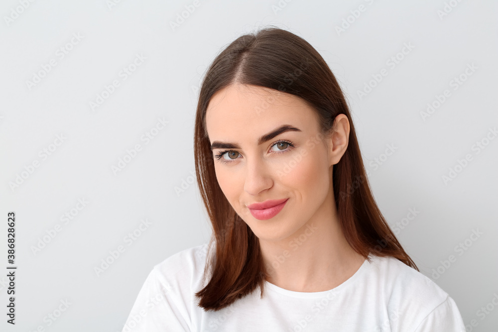Beautiful young woman on light background