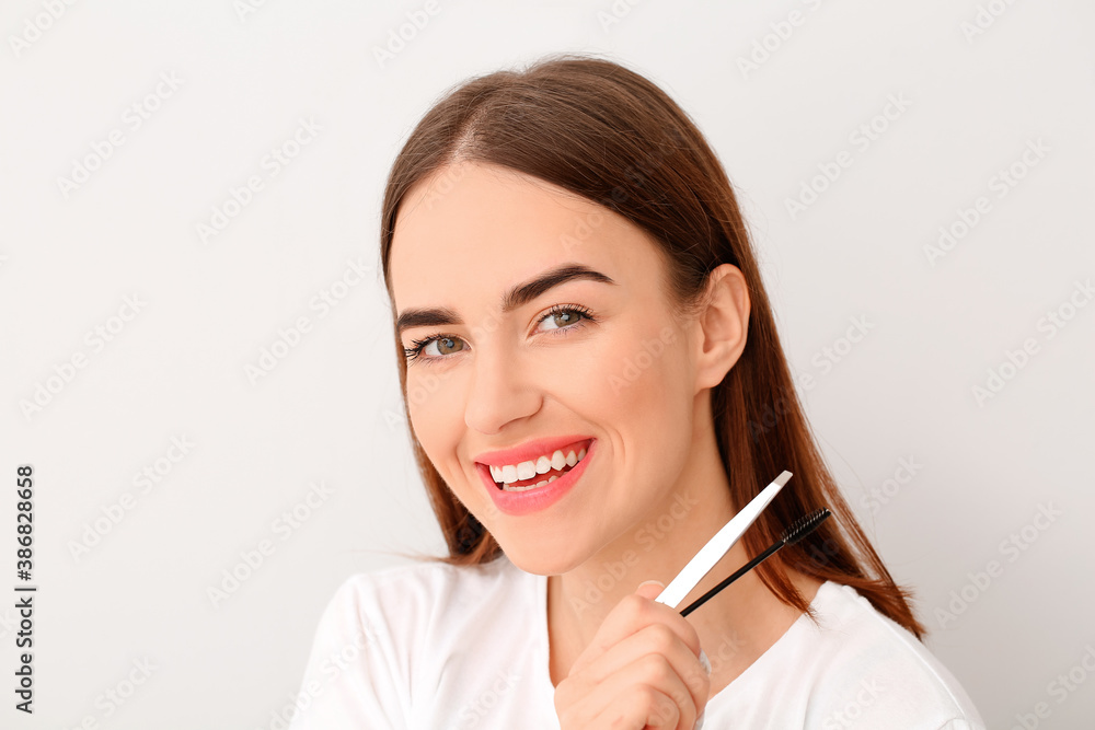 Young woman with tools for eyebrow correction procedure on light background Young woman with tools for eyebrow correction procedure on light background