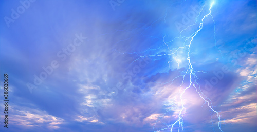 Lightning strikes between blue stormy clouds.