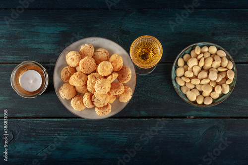 Amaretti, traditional Italian almond cookies, with a glass of Amaretto liqueur, shot from above on a dark blue wooden background