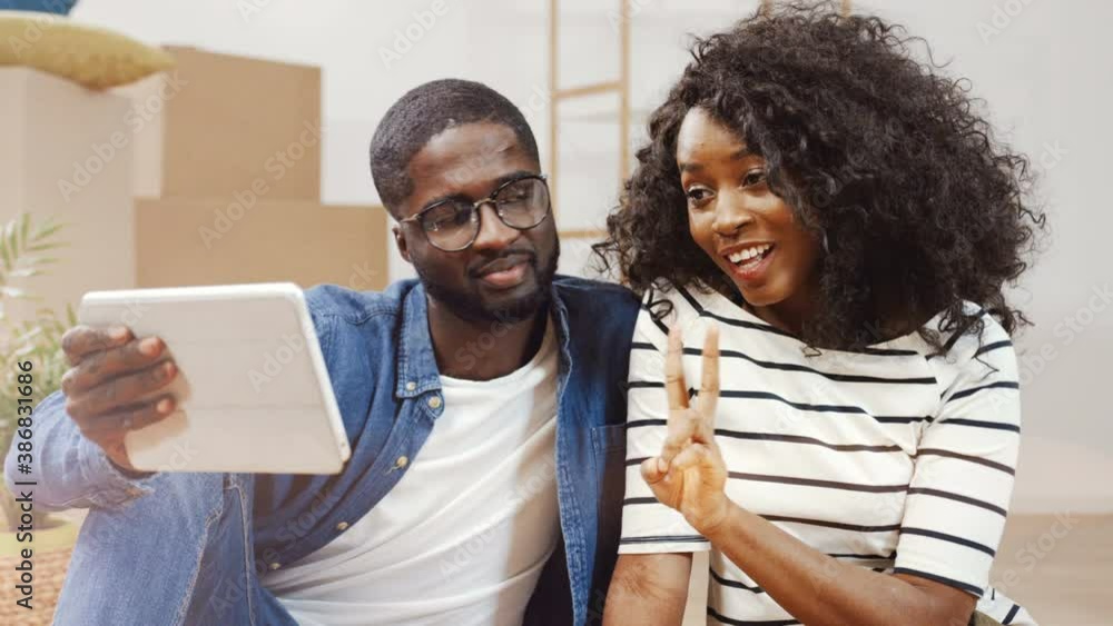 Portrait of happy young couple moved to new apartment. Handsome man holding tablet in his hands. Couple taking selfie photo on digital tablet. Portrait of happy young couple moved to new apartment. Handsome man holding tablet in his hands. Couple taking selfie photo on digital tablet.